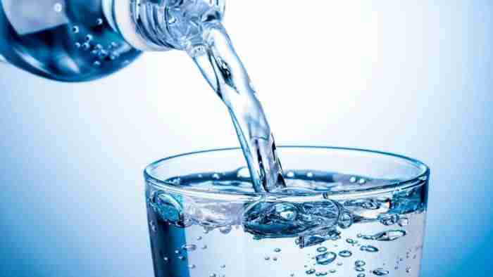 Clean water being poured into a glass cup from a bottle